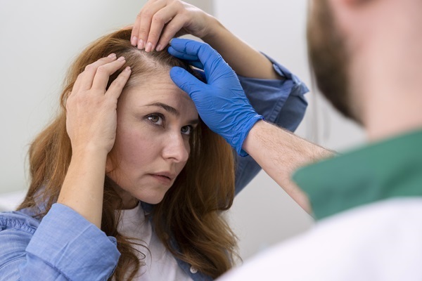 Médico especialista evalúa la pérdida de pelo en una mujer joven