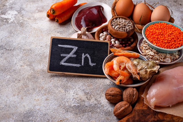 alimentos ricos en Zn sobre una mesa con una pizarra con el símbolo químico del metal