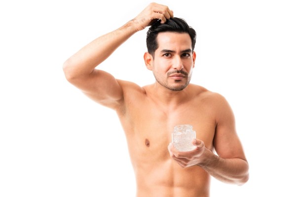 hombre aplicando un gel para el cabello en su melena
