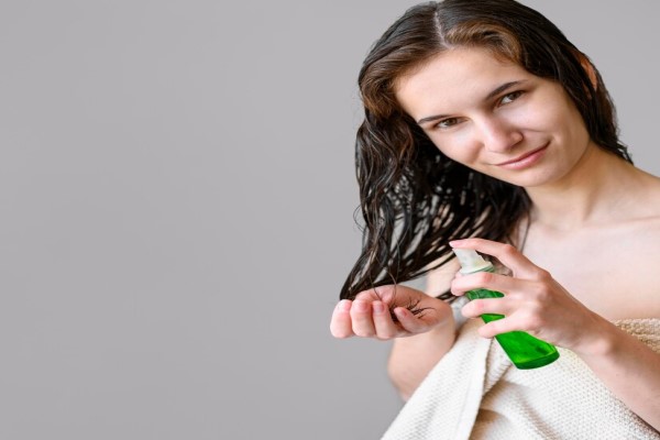 mujer joven después de la ducha aplicando un tratamiento capilar a las puntas de su cabello