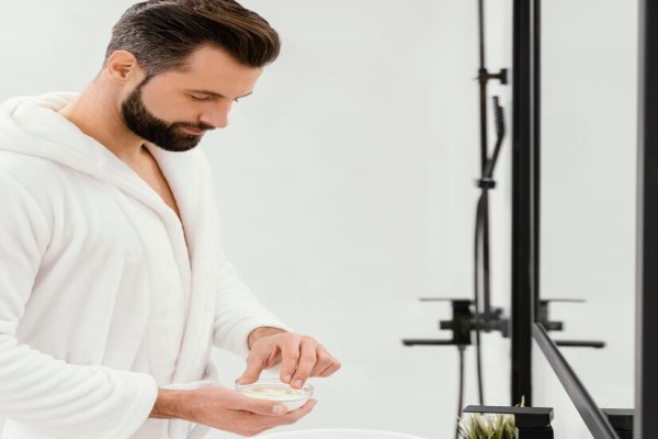 hombre aplicando un gel capilar para el cabello delante del espejo del baño