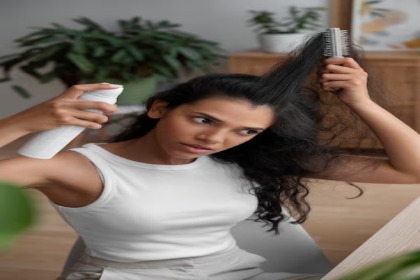 mujer usando un spray para desenredar el cabello mientras se cepilla la melena