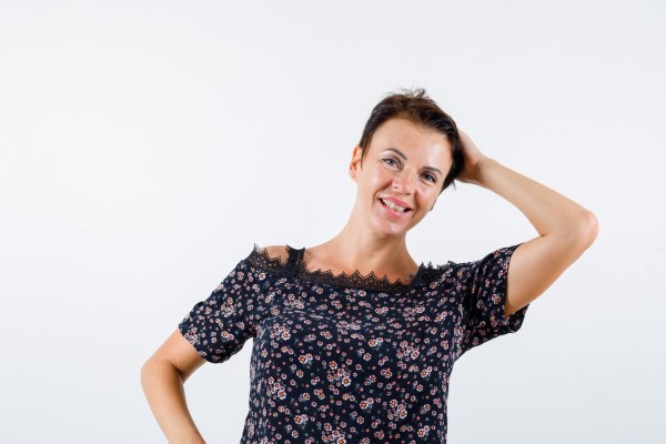 Mujer madura con la mano en la cabeza en blusa floral