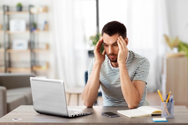 hombre estresado delante de la computadora con signos de alopecia en las entradas del cabello