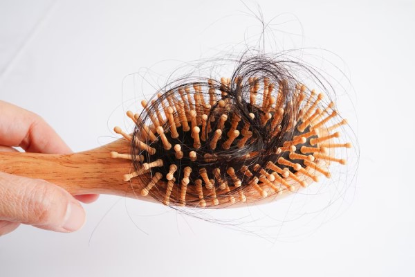 persona sujetando un cepillo con un mechón de pelo
