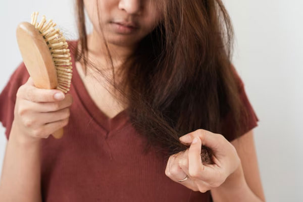 Caída del cabello - Joven con cepillo de madera en mano enfrenta una pérdida de cabello estacional 