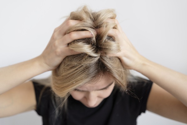 Contaminación - Mujer joven de cabello rubio con caspa rascando su cabeza