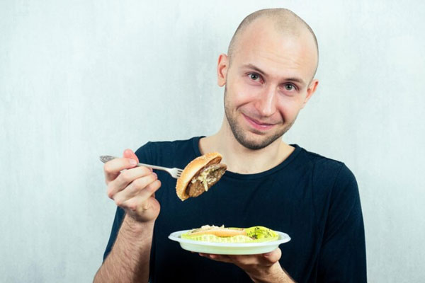 Caída del cabello - Retrato de hombre calvo comiéndose una gran hamburguesa de carne 