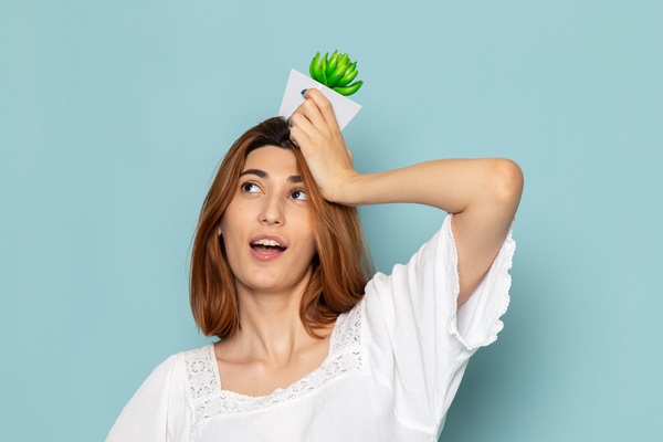 Vegetariano - Mujer de cabello castaño sosteniendo en su cabeza una planta