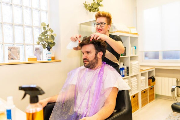 Sistema de integración capilar - Estilista ajusta una prótesis capilar en el cuero cabelludo de un paciente con alopecia