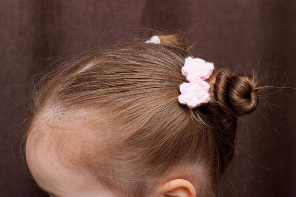 Peinados que debes evitar - Plano detalle de una niña con moños en el cabello favorecen la alopecia por tracción