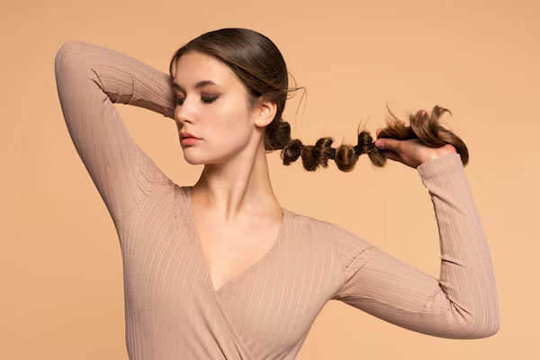 Peinados que debes evitar - Mujer utiliza ligas para hacerse un coleta moderna con su largo y abundante cabello