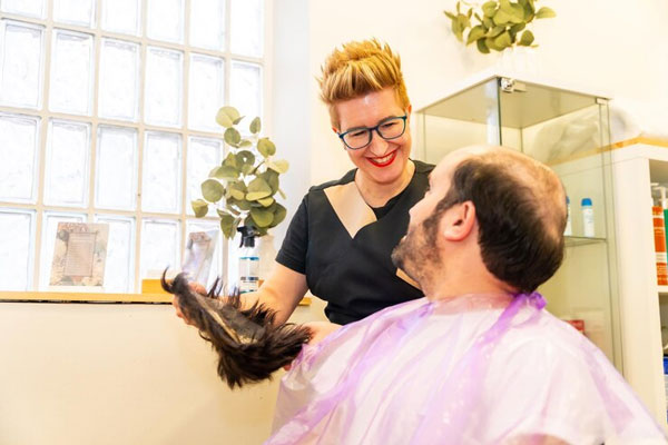 Estilista asesora a un hombre calvo para mejorar su apariencia con cabello postizo