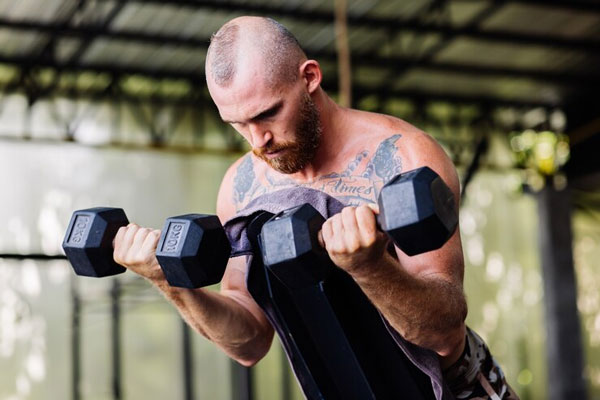 Esteroides anabólicos y alopecia - Hombre con problemas de alopecia hace ejercicio para estimular la hipertrofia muscular 