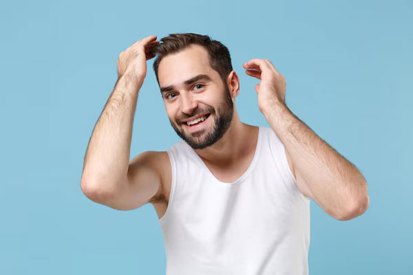 Joven sonriente disfruta de los primeros resultados de un trasplante de cabello exitoso 