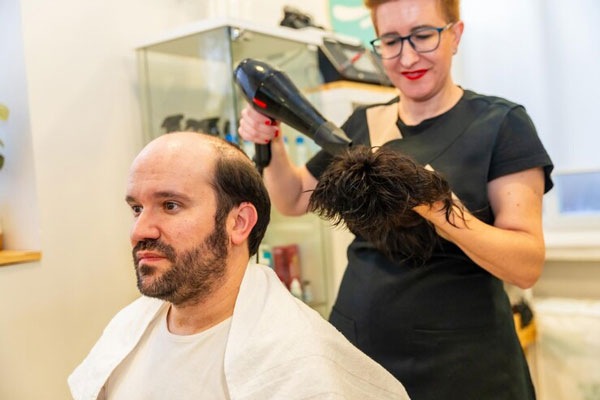 Estilista utiliza el secador para terminar de secar y hacerle mantenimiento a una prótesis capilar
