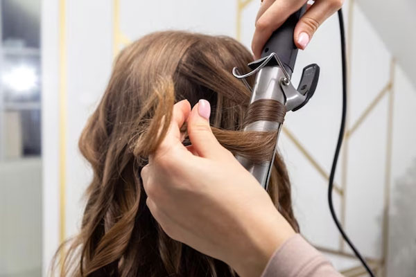 Peinados que debes evitar - Estilista utiliza un rizador para crear ondas tipo waffle en el cabello de un cliente