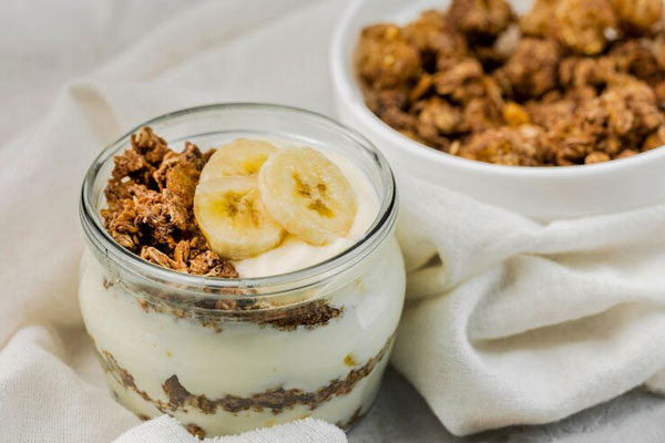Yogur griego con plátano, granola y frutos secos como fuente de calcio y proteínas esenciales 