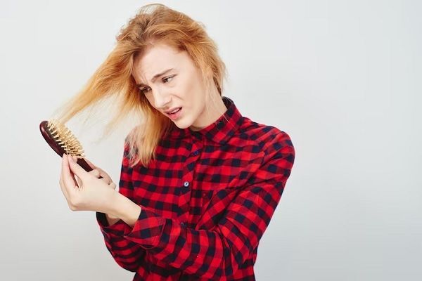 desenredar el pelo - joven cepillándose el pelo enredado que se queda enganchado en el cepillo