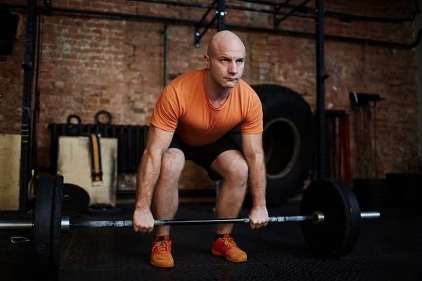 Esteroides anabólicos y alopecia - Hombre calvo levanta pesas como parte de su rutina de entrenamiento físico 