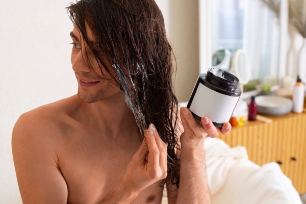 hombre aplicando un mascarilla capilar hidratante a su cabello para recuperar sus pelos quemados