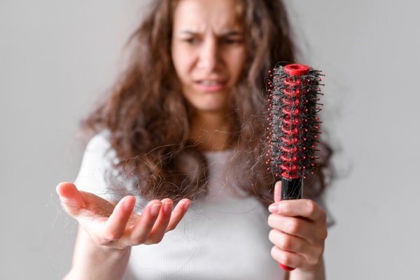 Cabello en invierno - Mujer observando que el cabello se cae en invierno con cara de preocupación