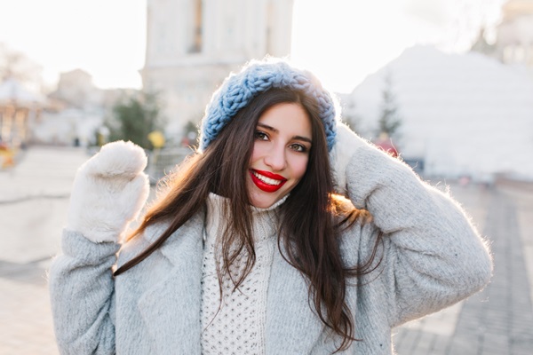 Cabello en invierno - Mujer usando un gorro para cuidar el cabello en invierno mientras visita una ciudad con nieve