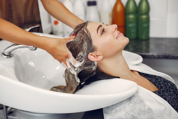 Cabello en invierno - Mujer en una peluquería aplicándose un champú y acondicionador hidratante para el cuidado del cuero cabelludo