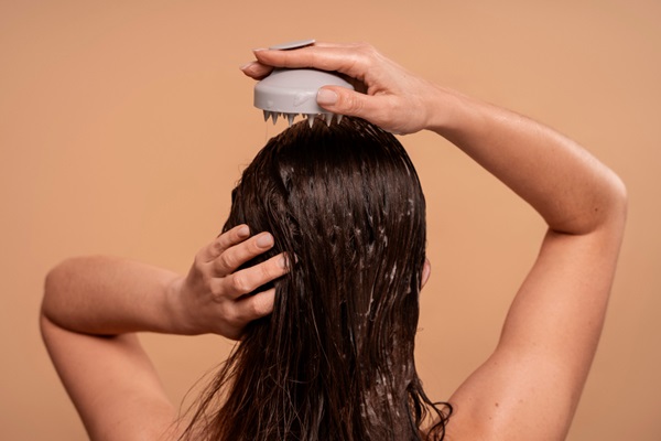 Mujer dándose un masaje en el cuero cabelludo para estimular el crecimiento del pelo