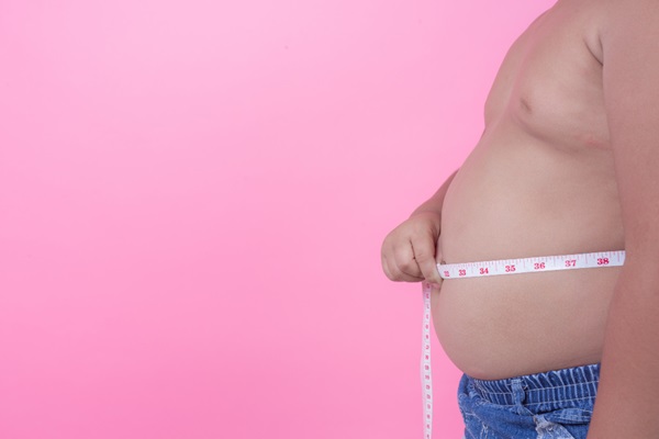 Calvicie y obesidad - Hombre midiendo con una cinta métrica su barriga debido a la obesidad