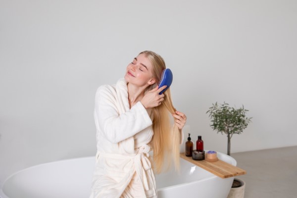desenredar el pelo - joven cepillándose el cabello antes de lavarlo para poder desenredar el pelo mejor después