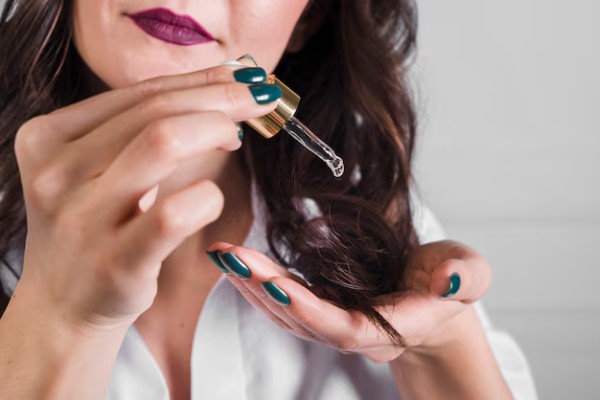 mujer adulta aplicando un aceite esencial a las puntas del cabello para facilitar el desenredo del cabello