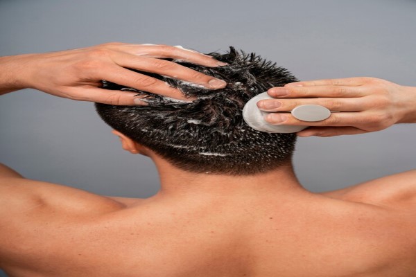 hombre usando un masajeador para el cuero cabelludo con una mascarilla capilar