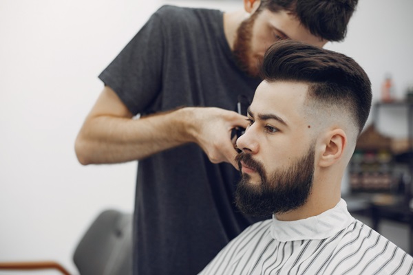 Cortes de pelo para hombres - Barbero afeitando a un hombre con un corte degradado para crear un look moderno