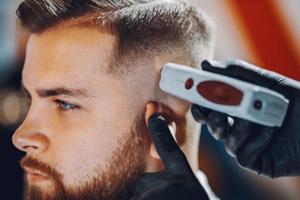 Cortes de pelo para hombres - Barbero utilizando una máquina para realizar un corte de pelo undercut a un hombre con barba