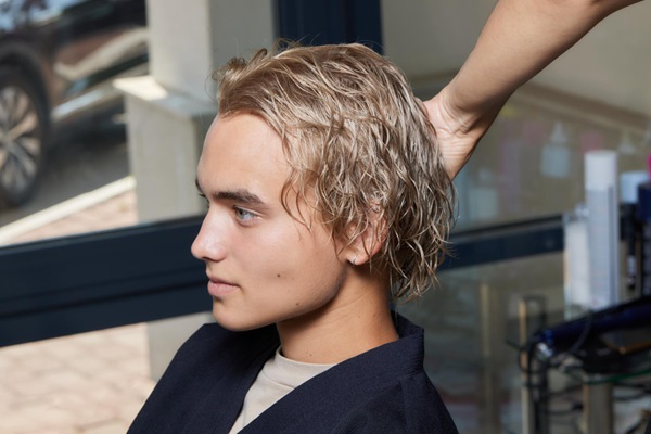 Cortes de pelo para hombres - Hombre joven en una barbería con un corte de pelo en capas para una apariencia moderna