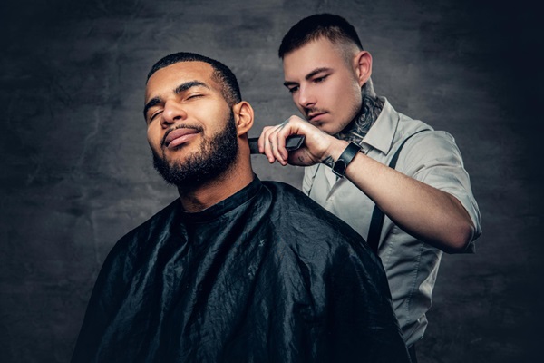 Barbero cortando el cabello con un estilo César a un cliente masculino