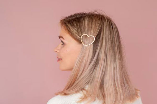 Mujer de pelo liso y teñido usa un pasador metálico para darle un toque de estilo a la melena