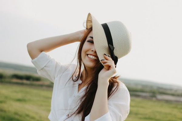 Accesorios para el cabello - Mujer sonriente usa un sombrero para realzar su look al aire libre