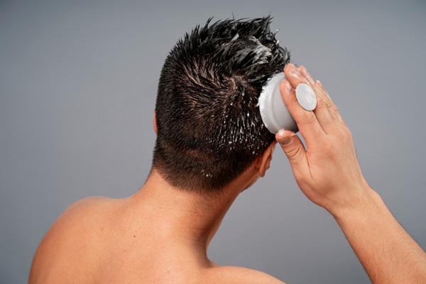Caballero realizando un masaje al cuero cabelludo mientras lava su cabello con champú