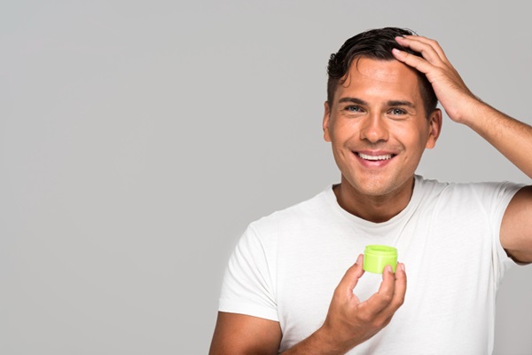 Hombre sonriente aplicándose gel de cabello para peinar
