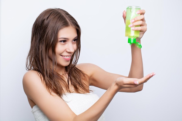 Pelo graso - Mujer joven utilizando un champú para cabello graso que ayuda a regular la producción de grasa