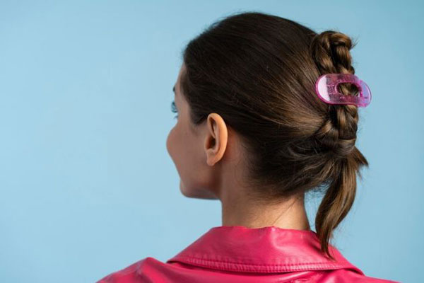 Accesorios para el cabello - Joven de espaldas usa una pinza para el pelo favoreciendo la alopecia por tracción