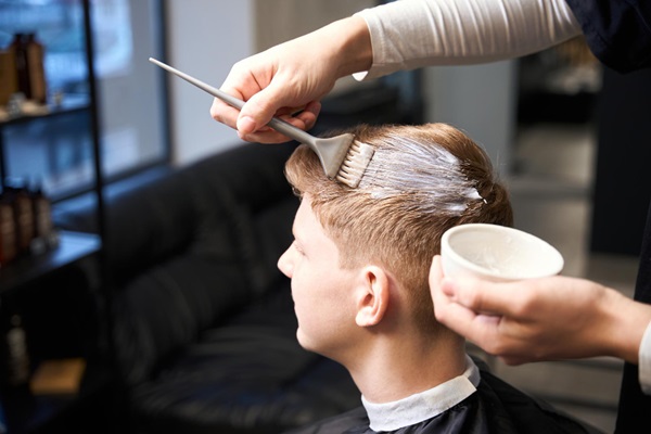 Teñirse el pelo tras injerto capilar - Estilista aplicando un tinte en el cabello de un hombre joven