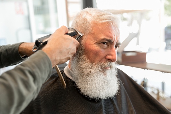 Cortes de pelo para calvos - Estilista cortando el pelo de un hombre mayor para hacer un peinado que cubre las zonas con pérdida de cabello