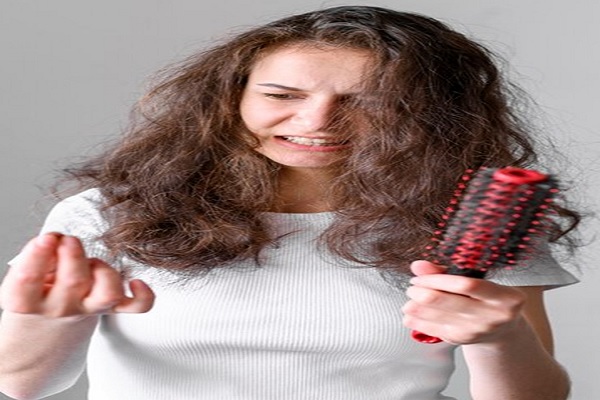 cae el pelo- Chica mirando los cabellos dejados en su cepillo al peinarse