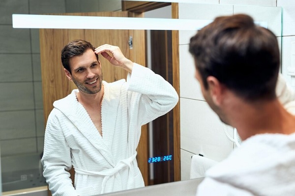 revisar el cabello- Hombre mira su pelo frente al espejo