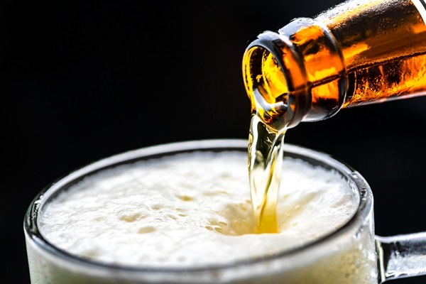 Aclarar el pelo - Imagen de una botella de cerveza siendo servida en un vaso de vidrio, uno de los productos naturales para aclarar el pelo