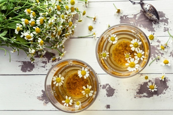 Aclarar el pelo - Vasos con infusión de té junto a varias flores de manzanilla la cual es beneficiosa y funciona para decolorar el cabello