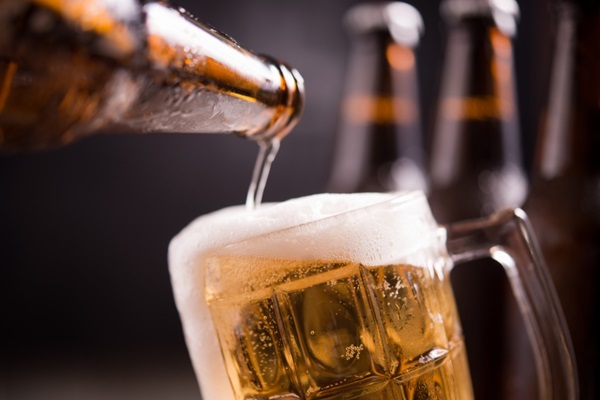 Cerveza para el cabello - Persona vaciando una botella de cerveza en un vaso de vidrio ya que la cerveza ayuda a estimular el crecimiento del cabello
